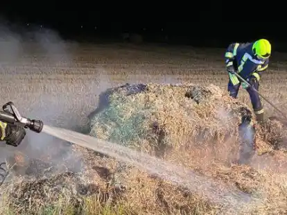 Die Kameraden beim L&ouml;schen des hei&szlig;en Strohs.