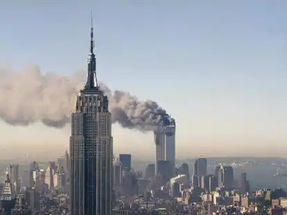 Die Zwillingst&uuml;rme des World Trade Centers brennen hinter dem Empire State Building. Am 11. September 2001 hatten islamistische Terroristen drei gekaperte Flugzeuge in das World Trade Center in New York und das Pentagon in Washington gesteuert. Foto: Marty Lederhandler/AP/dpa