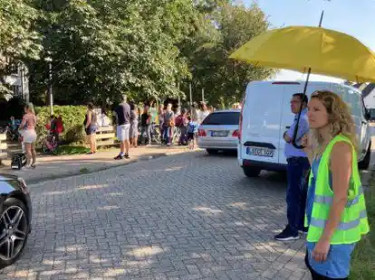 Schmale Stra&szlig;e mit flie&szlig;endem und stehendem Verkehr in beide Richtungen auf dem Die&szlig;elweg direkt vor der Grundschule Krusenbusch: Marje L&uuml;ck (re.) und die Eltern des Verkehrsausschusses der Schule m&ouml;chten, dass die Kinder hier bald sicherer zur Schule kommen k&ouml;nnen.