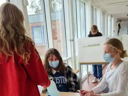 Auch die Organisation wird bei der Juniorwahl von den Sch&uuml;lern &uuml;bernommen: Maximilian M&auml;mpel (vorne) l&auml;sst sich von den Wahlhelferinnen Ana Ramirez (links) und Ina Haverkamp den Stimmzettel aush&auml;ndigen. Nico Fischer (hinten) ist schon in der Wahlkabine.