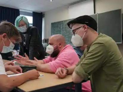 <p>Hauke Schrade (in Pink) und Mirco Gilster (rechts) helfen Zehntkl&auml;sslern der Oberschule Harpstedt beim Verfassen von Poetry-Slam-Texten.Nils Hannes Klotz</p>