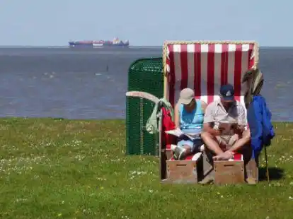 Am Strand von Burhave genie&szlig;t ein Urlauberpaar die letzten warmen Tage des Jahres.