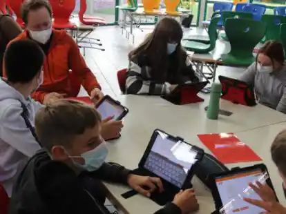 Online-Diagnose an der IGS Bar&szlig;el: Die Sch&uuml;lerinnen und Sch&uuml;ler testen ihr Wissen mit Online-Tests auf dem Tablet. Dabei hilft auch Lehrer Tobias Brossmann (hinten).