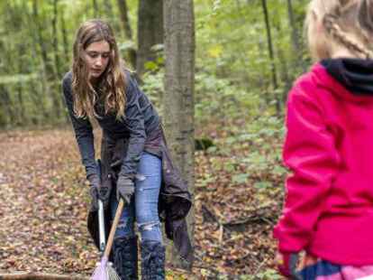 Marleen (rechts) und Schwester Amelie beim Laubharken auf dem Weg