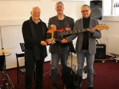Udo Knirr (von links) &uuml;berreicht Thomas Schr&ouml;der und Ulrich Ziegeler mit Musikschulhund Woody ein begehrtes Instrument: einen E-Bass der Marke Luxor.