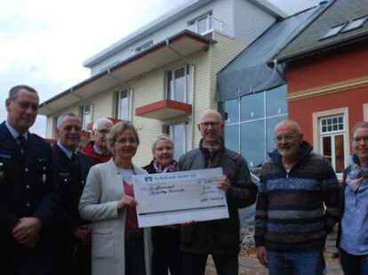 Silke Meents und ihr Mann Arno (2. von rechts) &uuml;berreichten an den Vorsitzenden des F&ouml;rdervereins der jeverschen Feuerwehren, Helmer Sch&ouml;nheim, einen Spendenscheck. F&uuml;r die Feuerwehren mit dabei waren Joachim Helmerichs und Torsten Schoster, Hans-Hermann Specht und Saskia Reger vom F&ouml;rderverein und Architektin Jasmin Eilers.