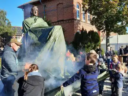 Die Enth&uuml;llung des Aper Wahrzeichens: Ritter Herbord von Apen verbirgt sich unter der Plane, die von den Kindern gel&uuml;ftet wird. Es ist die 15. und letzte Skulptur der Aper Lieblingsorte.