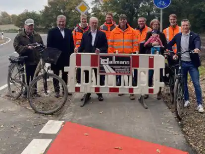 R&auml;umen die letzte Absperrung aus dem Weg (v.l.): Clemens Langemeyer (Anlieger), B&uuml;rgermeister Gerd Meyer, Hendrik Bramlage (Leiter Kreisstra&szlig;enmeisterei), Landrat Herbert Winkel, Michael Schw&auml;rter (Bauwart), Gerd W&ouml;rdemann (Firma Dallmann), Carina Burhorst mit Tochter Frieda (Anlieger), Markus Bl&ouml;mer (Sachgebietsleiter Tiefbau) und der Kreistagsabgeordnete Andr&egrave; H&uuml;ttemeyer.