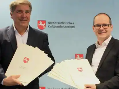 Niedersachsens Kultusminister Grant Hendrik Tonne (rechts) &uuml;berreichte Oberb&uuml;rgermeister J&uuml;rgen Krogmann gleich zw&ouml;lf Bewilligungsbescheide aus dem Digitalpakt Schule.