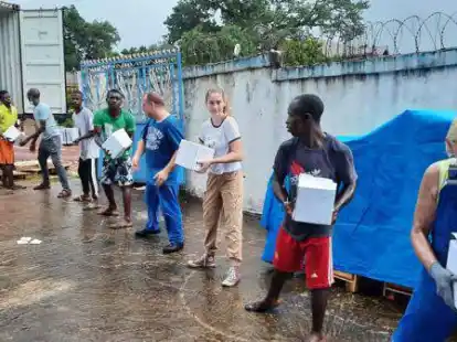 Alle packen mit an: Gisela Bednarek (rechts) reiht sich ein beim Entladen der Fliesenpakete  in Sierra Leone.