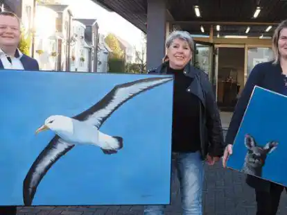 Christian G&ouml;rres, Dagmar Morgenstern und Melanie Gloystein (von links) pr&auml;sentieren zwei Werke, die in der Filiale auch zu sehen sind.