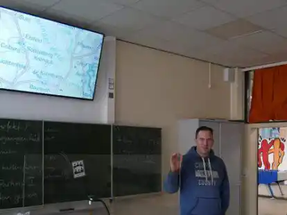 Der Lehrer Carsten Freels zeigt in der Klasse 8P der Oberschule Rodenkirchen den neuen Smart-Fernseher &uuml;ber der altbekannten gr&uuml;nen Tafel, die erhalten bleibt.