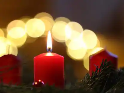Eine Kerze brennt am ersten Advent an einem Adventskranz.
