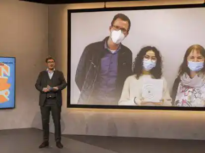 Moderator Desimo stellt das Gewinnteam des Gymnasiums vor: Lehrer Oliver Voigt, Sch&uuml;lerin Amelie M&uuml;ller und Schulleiterin Silvia Warns.