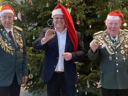 Weihnachtsm&uuml;tze statt Sch&uuml;tzenhut: Nur noch 600 Pins m&uuml;ssen Klaus Bohmann, Landrat Tobias Gerdesmeyer und Sch&uuml;tzenkreispr&auml;sident Walter Thie (von links) bis zum Spendenziel verkaufen.