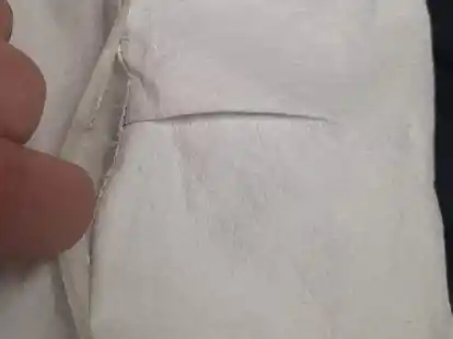 Ein Feuerwehrmann zeigt einen gel&ouml;sten Abdeckstreifen mit aufgerissener Naht.