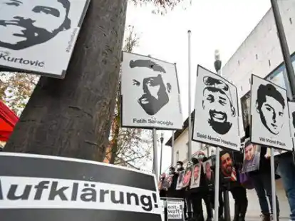 Angeh&ouml;rige der Opfer des rassistischen Anschlags von Hanau 2020 halten bei einer Mahnwache vor dem hessischen Landtag Fotos der Opfer.