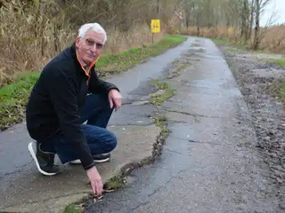 An einigen Stellen sind die Risse im Niensweg so breit, dass ein Fu&szlig; hineinpasst, wie Anlieger Dieter Brandt zeigt.