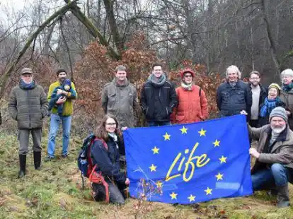 Exkursionsteilnehmer vor der Flagge des von der EU gef&ouml;rderten Flora-Fauna-Habitat-Projektes.