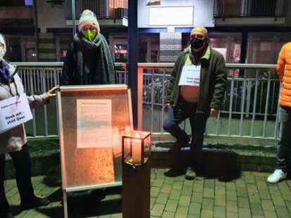 Eine Kerze brannte zum Gedenken an die Opfer der Pandemie. Das Bild zeigt Gisela Verbeek (v.l.), Sarah Czychowski, Klaus-Dieter Jakob und Sebastian Zwiener an der Stelltafel mit einem Text, den Pastorin Wielage formuliert hatte.