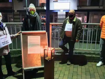 Eine Kerze brannte zum Gedenken an die Opfer der Pandemie. Das Bild zeigt Gisela Verbeek (v.l.), Sarah Czychowski, Klaus-Dieter Jakob und Sebastian Zwiener an der Stelltafel mit einem Text, den Pastorin Wielage formuliert hatte.