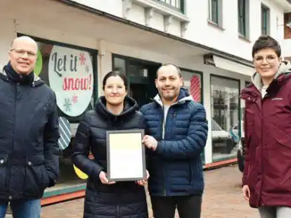 Gert K&uuml;hling (l.) und Anne Nu&szlig;waldt (r.) &uuml;bergaben die Urkunde an Dina Manuela und ihren Ehemann Filipe Morais vor ihrer k&uuml;nftigen Eisdiele.