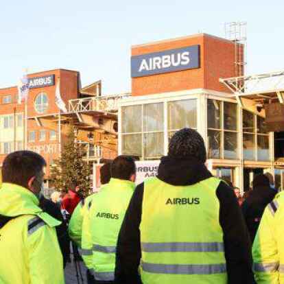 W&auml;hrend einer Aktion im Dezember zur Aufsichtsratssitzung von Airbus stehen Mitglieder der IG Metall mit Transparenten und Schildern vor einem Werkstor von Airbus in Hamburg-Finkenwerder.