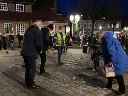 Blumen f&uuml;r die bisher 133 Todesopfer im Landkreis im Zusammenhang mit der Corona-Pandemie wurden am Montagabend auf dem Wildeshauser Marktplatz abgelegt. Im Hintergrund waren Pfiffe von Kritikern der Corona-Ma&szlig;nahmen zu h&ouml;ren.