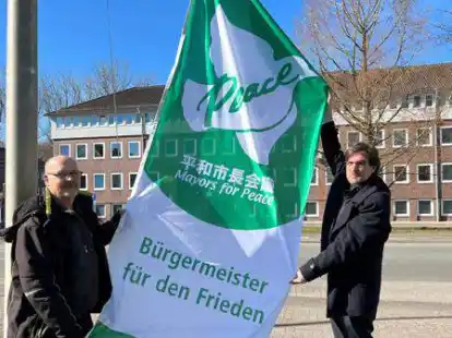 Hausmeister Gunnar Emmert (links) und Stadtoberhaupt Nils Siemen hissten das Friedensbanner vor dem Rathaus.