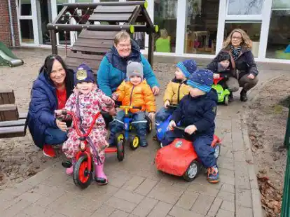 Dank neuer Pflasterung gibt es auf dem Spielplatz der Krippe in Altmoorhausen jetzt einen Rundkurs, auf dem die J&uuml;ngsten sich mit Bobbycar, Laufrad oder Dreirad austoben k&ouml;nnen. Dar&uuml;ber freuen sich mit den Kleinen die Kinderpflegerinnen Doris Ahlers und Angela Gerdes mit Kita-Leiterin Vanessa Bohlen.