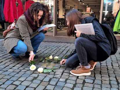 Maike Olthoff (Jahrgang 12) und Cosima Artmann (Jahrgang 11) vom Beruflichen Gymnasium der BBS II Emden legen in der Gro&szlig;en Stra&szlig;e Rosen f&uuml;r die j&uuml;dische Familie Gans nieder.