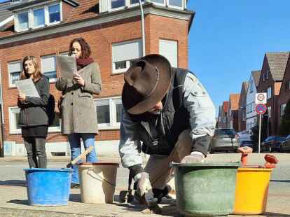 Stolperstein-Verlegung in der Gro&szlig;en Stra&szlig;e: W&auml;hrend Cosima Artmann und Maike Olthoff vom Beruflichen Gymnasium der BBS II Emden die Opferbiografien von Arent, Kornelia, Simon und Ludwig Gans verlesen, setzt Gunter Demnig die Stolpersteine ins Gehwegpflaster.