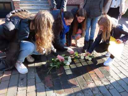 Sch&uuml;lervertreterinnen des Max-Windm&uuml;ller-Gymnasiums legen wei&szlig;e Rosen f&uuml;r die Familie Hartogsohn nieder.