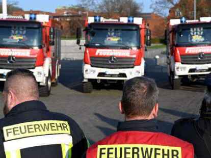 Feuerwehrm&auml;nner stehen vor neuen L&ouml;schfahrzeugen. Nat&uuml;rlich sind alle in Fluchtrichtung aufgestellt, denn so macht man es bei der Feuerwehr.