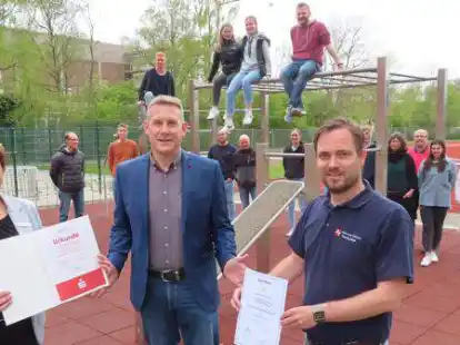 Gemischtes Doppel im Calisthenics-Park des JAG: Insa Bruns-Breninck von der Sparkasse Emden &uuml;berreichte an Schulleiter Oliver Damm die Urkunde f&uuml;r den dritten Platz im bundesweiten Sportabzeichen-Wettbewerb, Schulsport-Fachberater Henning Bach die Urkunde zur Auszeichnung als &bdquo;Sportfreundliche Schule&ldquo;.