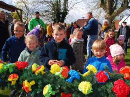 Letzte Hand am Blumenschmuck: Kinder aus Moorwarfen begutachten den Baum, der in wenigen Augenblicken aufgerichtet werden soll.