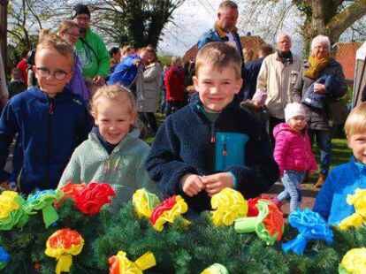 Letzte Hand am Blumenschmuck: Kinder aus Moorwarfen begutachten den Baum, der in wenigen Augenblicken aufgerichtet werden soll.