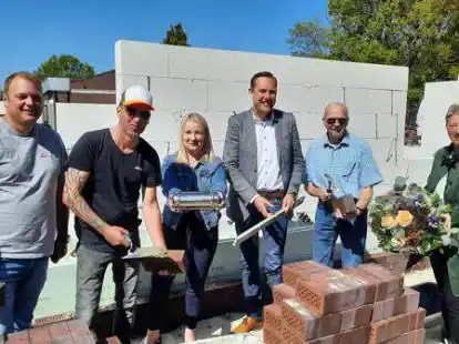 Grundsteinlegung f&uuml;r ein neues Wohn- und Gesch&auml;ftshaus in Apen: Bauunternehmer Alex Timmermann (von links), die Bauherren Matthias Brand-Peters und Britta Peters, B&uuml;rgermeister Matthias Huber, Bezirksvorsteher Albrecht-Erich Krause und Ulrike L&ouml;ffel-Harms vom Gewerbekreis.