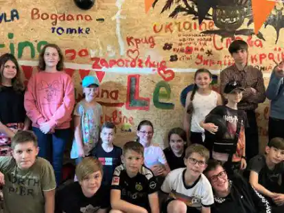 Die Kinder und Jugendlichen sowie Caroline Ludewig (links), Leiterin des Jugendhauses, freuen sich &uuml;ber ihren neuen Treffpunkt in Oldenbrok. Auf der Wand haben sie sich bei der Er&ouml;ffnung mit Bildern und Schriftz&uuml;gen verewigt.