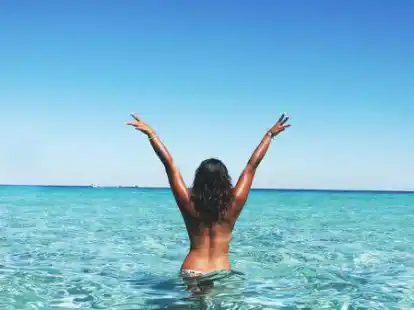 Eine Frau ist ohne Bikini-Oberteil baden.