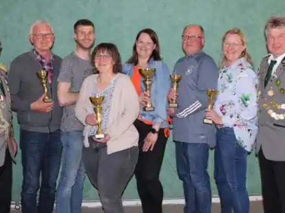 Pokale &uuml;berreichten Vereinsvorsitzender Martin Oltmann (l.) und  Vereinsschie&szlig;meister Matthias Skaczylas (r.) an (von links) Klaus Evers (Team Werkstatt), Dennis Skaczylas (Team Bier geht immer), Martina Sprock (Team Planwagen), Sabrina Oltmann (Team Siedlerbund), Rainer Oltmann (Team Heimatverein B&ouml;sel, Bezirk Westerloh) und Bianca Saulen (Chor B&ouml;sel).