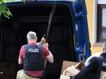 Polizisten tragen Gegenst&auml;nde, darunter mehrere Stichwaffen und Speere, aus dem Wohnhaus des Verd&auml;chtigen in Essen.