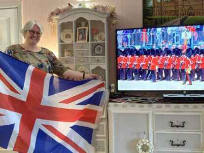Stolz posiert Ruth Offermann mit der Flagge Gro&szlig;britanniens neben ihrem Fernseher, wo gerade eine Milit&auml;rparade zu Ehren des Geburtstags von K&ouml;nigin Elizabeth l&auml;uft.