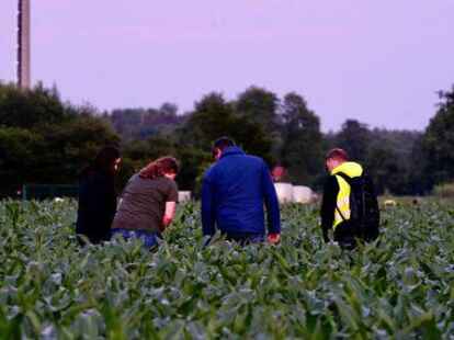 Pr&uuml;fender Blick: Zwei Mitarbeiter der Spurensicherung lassen sich von privaten Helfern die gefundenen Fu&szlig;spuren zeigen.