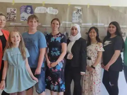 P&auml;dagogische Mitarbeiterin Heike K&uuml;hl (v. l.), Lena aus dem f&uuml;nften Jahrgang, Thorin aus dem siebten Jahrgang, Lehrerin Imke Beewen, Dooa, Shauna und Aleyna aus dem neunten Jahrgang und Lehrerin Ina Hinrichs stehen vor einem der Projekte, das an der OBS Sande zum Anne-Frank-Tag erstellt wurde.