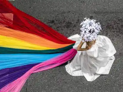 Eine Person tr&auml;gt einen Regenbogenschleier w&auml;hrend einer Parade zur Feier des Pride-Monats.