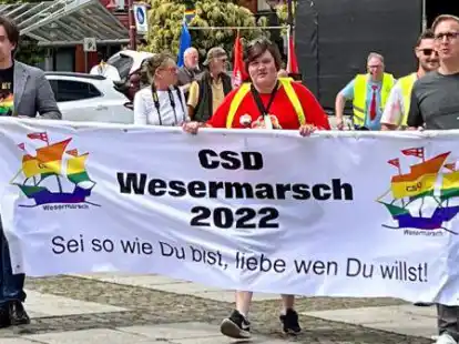 Nordenhams B&uuml;rgermeister Nils Siemen (links), Leon Wei&szlig; (Mitte) und Landrat Stephan Siefken pr&auml;sentieren das Motto des Christopher Street Days in Nordenham.