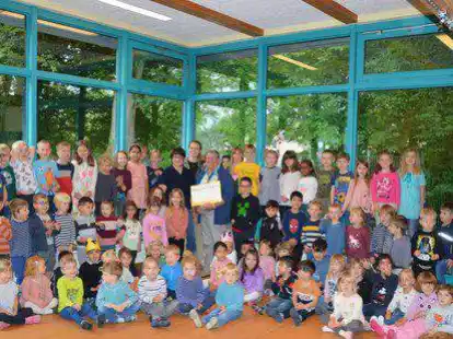 Spenden&uuml;bergabe inmitten von Kindern: Kitaleiterin Sabine Schneider &uuml;bergab den symbolischen Spendencheck an Louisa Blank (Vereinsvorsitzende) und Reinhold Weerts vom Verein &bdquo;Humanit&auml;re Soforthilfe Ammerland Ostfriesland&ldquo;.