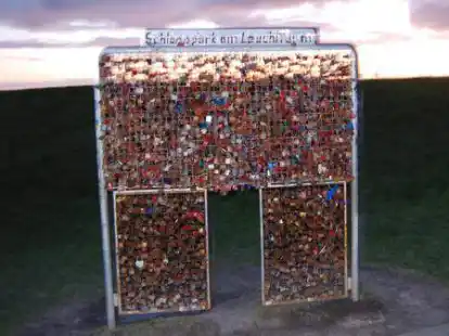 Romantik pur: Ein Liebesschloss am Pilsumer Leuchtturm bei Sonnenuntergang aufh&auml;ngen.