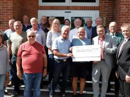 Flohmarktveranstalter Claas Meyer (vorne, 3. v.r.) &uuml;berreicht B&uuml;rgermeister Nils Anhuth (vorne, 2.v.r.) und dem Flohmarktgremium Elisabethfehn einen Scheck &uuml;ber 10.000 Euro.